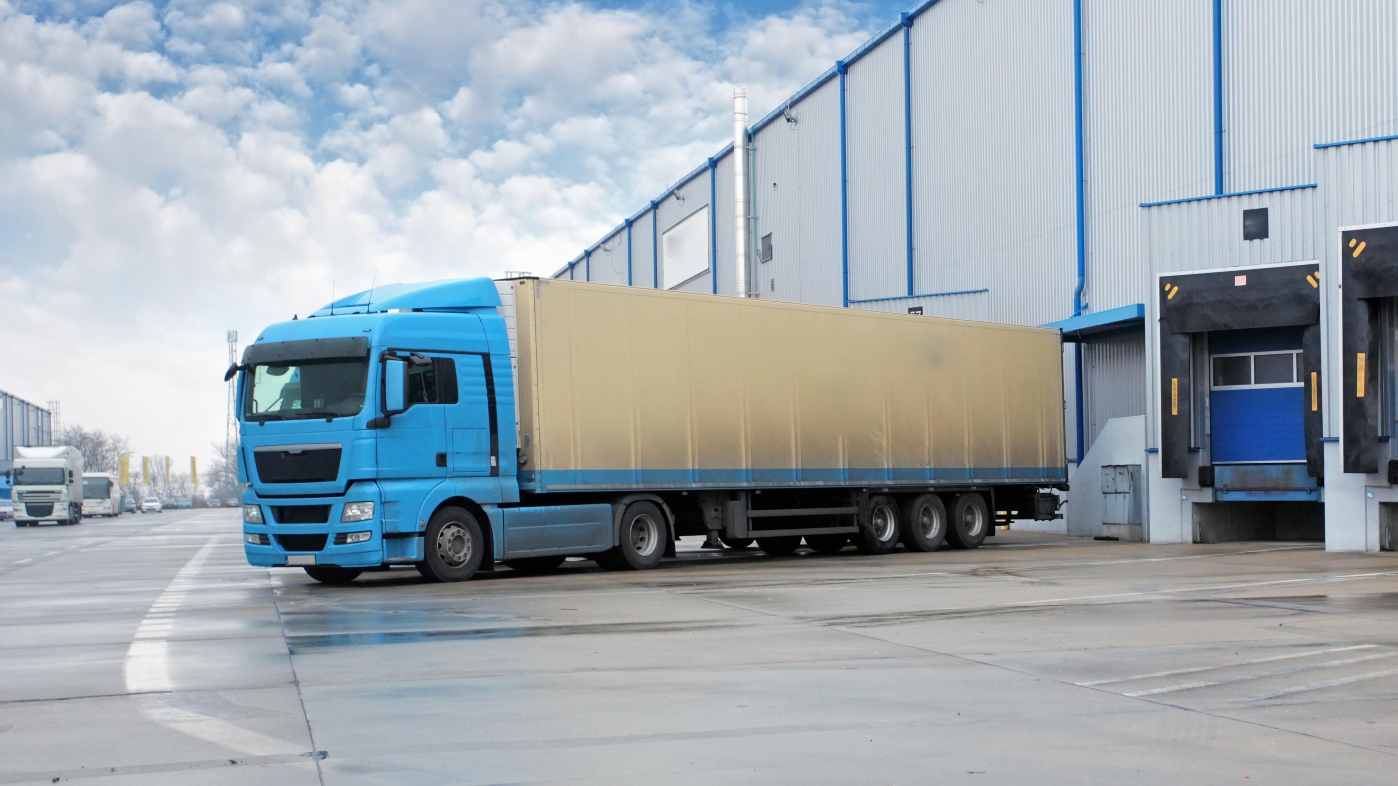 Blauer Liefer-Lkw an der Laderampe eines Logistikzentrums