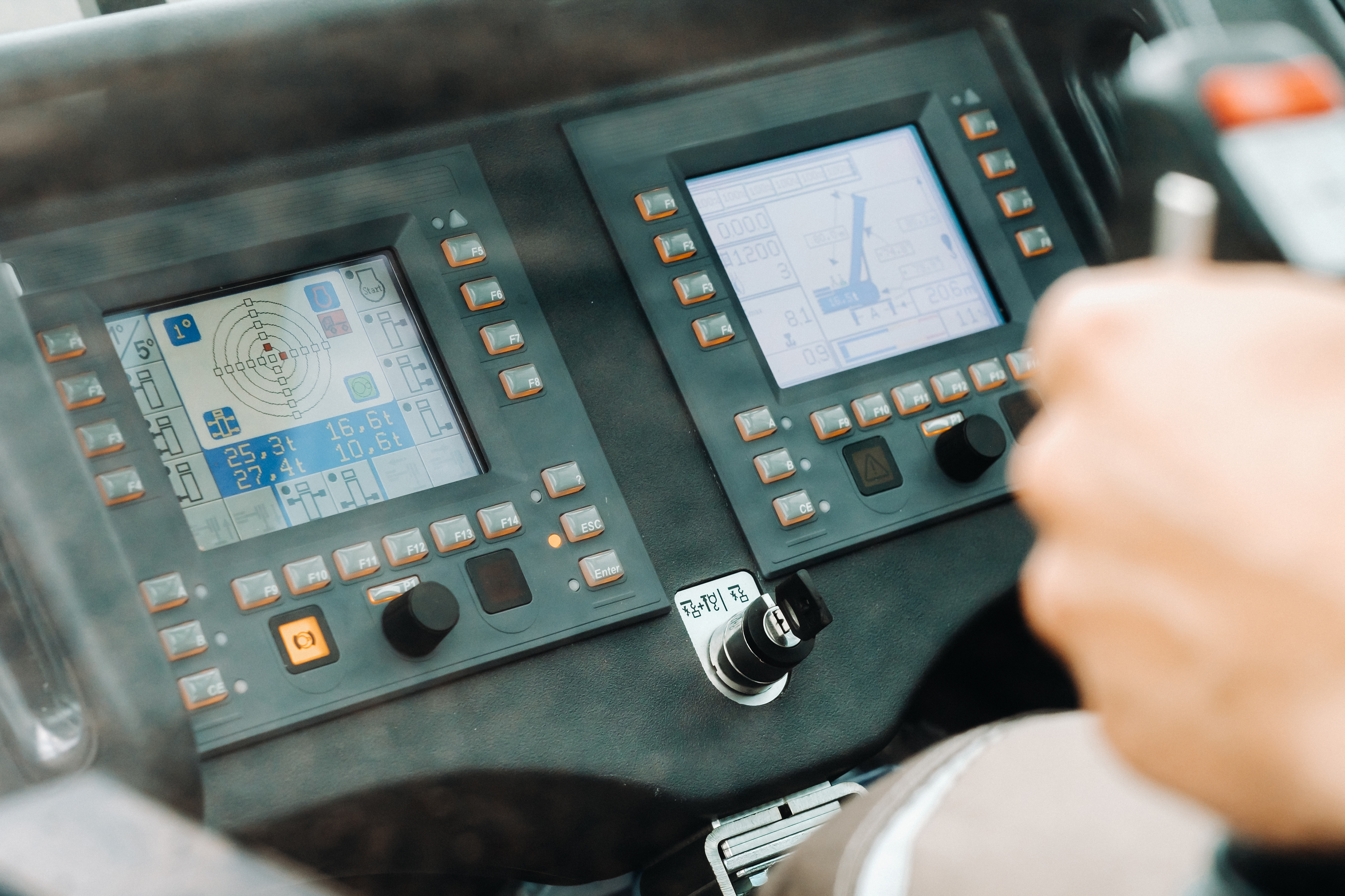 Bediener steuert einen Kran über digitale Bedienelemente und Monitoringsysteme